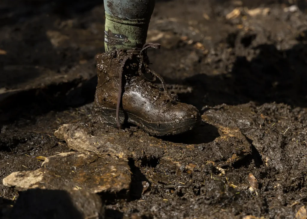 A person's foot, clad in a muddy hiking boot.