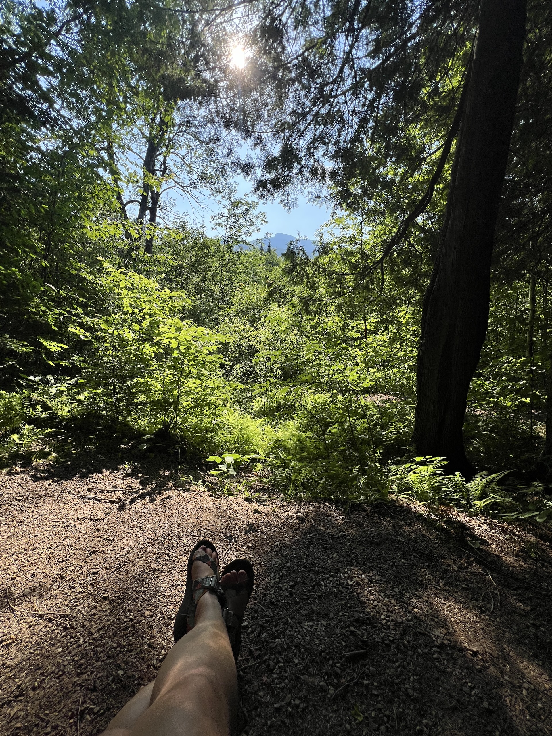 hiker resting on a bech with feet extended admiring view